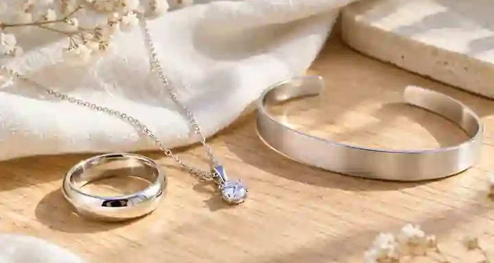 Ảnh minh họa nhẫn, dây chuyền và vòng bạc màu trắng sáng đặt trên nền gỗ sáng