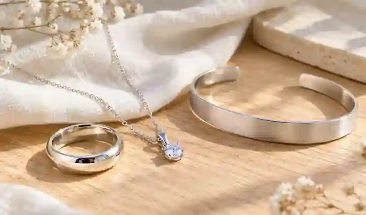 Ảnh minh họa nhẫn, dây chuyền và vòng bạc màu trắng sáng đặt trên nền gỗ sáng