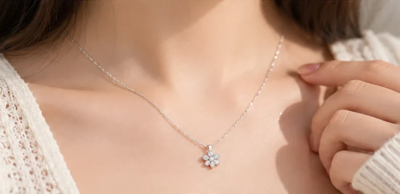 Dây chuyền bạc nữ sợi mảnh phối mặt hoa nhỏ trên cổ người mẫu mặc áo len màu kem