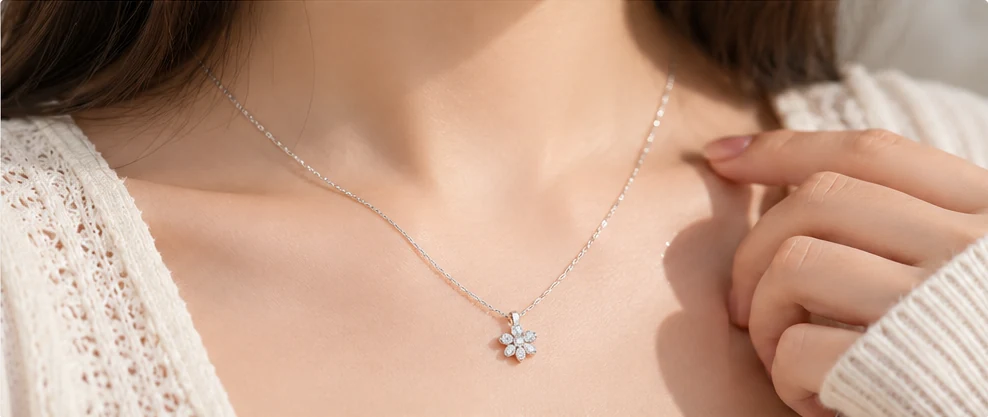 Dây chuyền bạc nữ sợi mảnh phối mặt hoa nhỏ trên cổ người mẫu mặc áo len màu kem