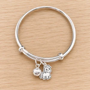 Vòng bạc hình con ngựa cho bé với bi bạc treo trên nền gỗ sáng