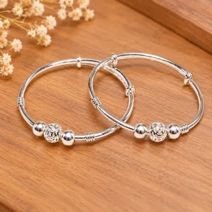 Hai vòng bạc ta trẻ em có ba bi bạc, họa tiết bi kim tiền, chụp trên nền gỗ